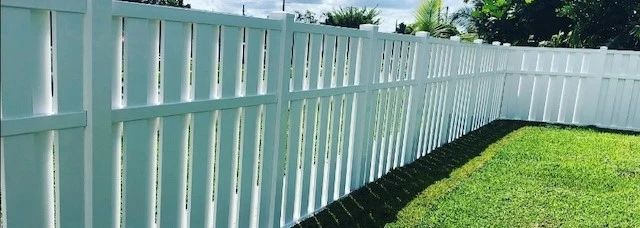 White PVC vinyl privacy fence panel under bright midday sunlight with uniform surface color showing no visible UV fading or chalking after years of exposure White PVC vinyl privacy fence panel under bright midday sunlight with uniform surface color showing no visible UV fading or chalking after years of exposure